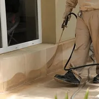 General pest control technician spraying exterior perimeter around a home in Jacksonville, FL