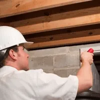 Termite inspection technician checking a basement wall and framing for termite activity in Jacksonville, FL